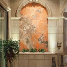 Eye-Catching Orange Onyx Water Wall Within A Strong, Stone Transition Space