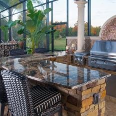 Luxurious Outdoor Kitchen Featues Ledgestone Bar, Granite Countertop & Curved Glass Tile Backsplash.