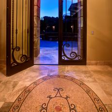 Mediterranean-inspired Foyer with Tall Arched Door and Inlaid Mosaic Tile Floor