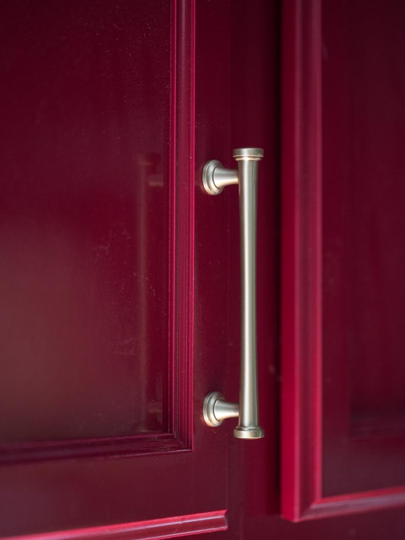 Sleek Satin Brass Pull on Red Kitchen Cabinet Door