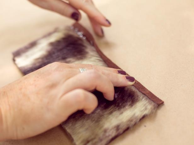 Flip the piece over so that it is fur side up. Run another thin line of glue along the edge where the fur and the excess felt meet, then quickly fold the excess felt over itself to finish the edge.