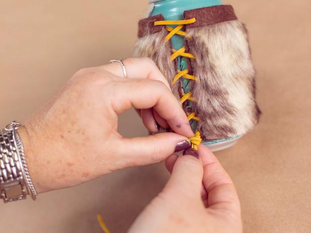 Wrap the fur around the can and run craft lace through the holes, starting at the top, working your way down. Tie off with a slip knot.
