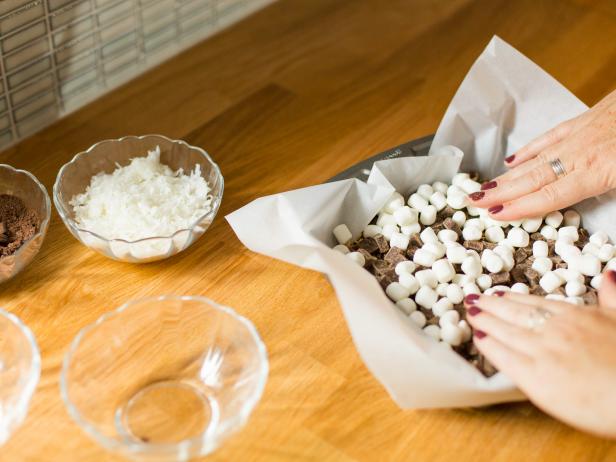 Layer on the toppings, starting with the chocolate chips, then add marshmallows, topping them with ground graham cracker. Finish off with a layer of shredded coconut.