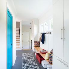 Long Mudroom With Turquoise Pocket Door and Patterned Rug