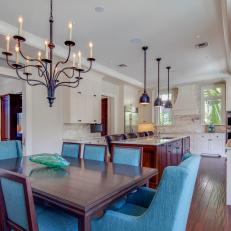 Bright Transitional Connected Eat In Kitchen and Dining Room With Blue Upholstered Chairs, Rich Wood Table and Metal Light Fixtures 