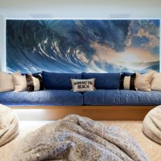 Rec Room with Wave Photo Art, Long Blue Sofa, Shag Carpet and Animal-print Beanbag Chairs. 