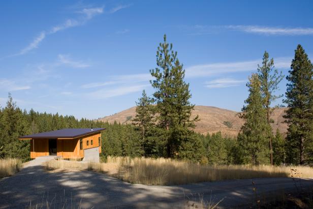 Small Modern Cabin Surrounded by Pine Trees and Hills