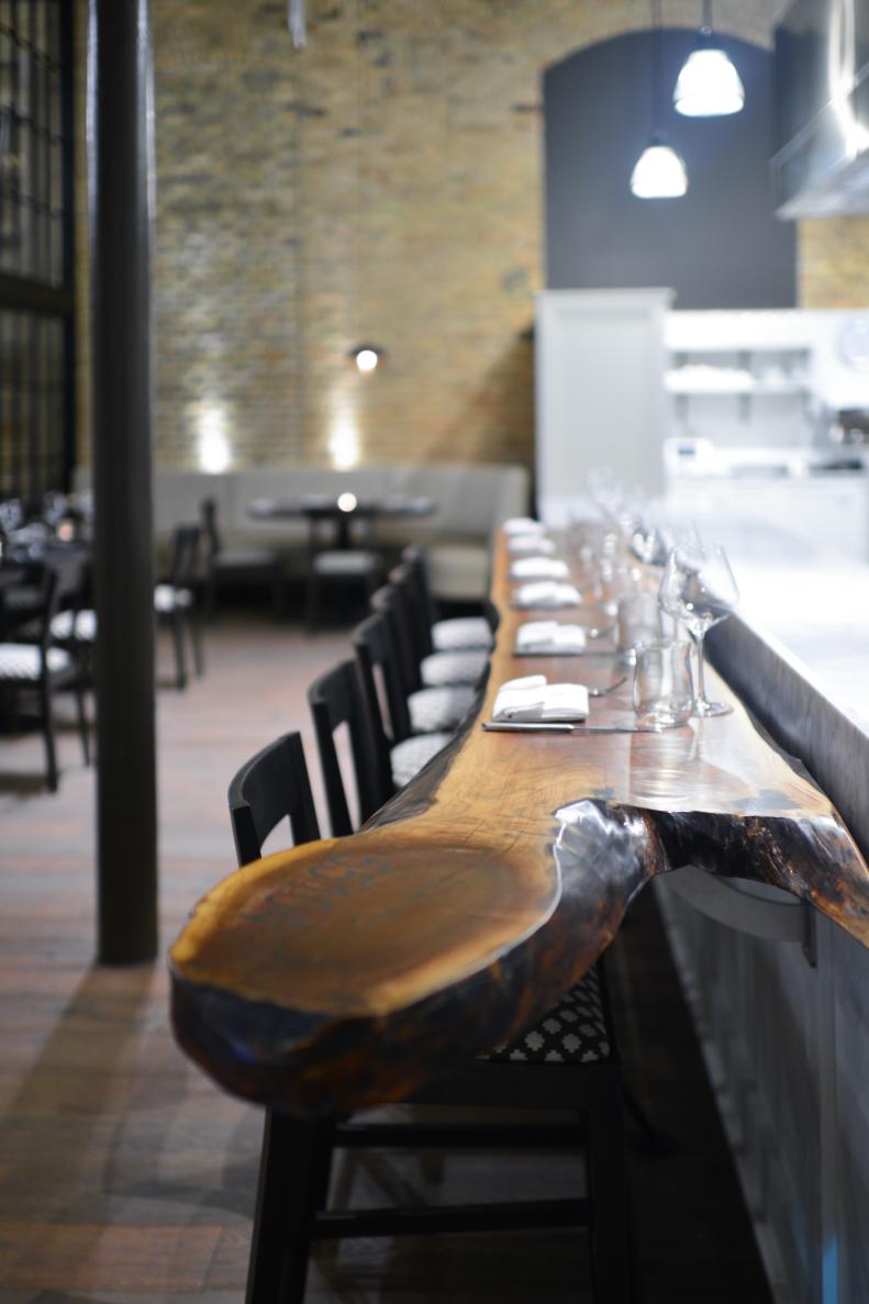 Black Chairs Lining Live-Edge Wood Counter in Restaurant