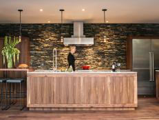 Galley Kitchen With Gray Stacked Stone Wall and Sleek Wood Island