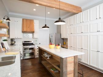 Fixer Upper Hosts Chip and Joanna Gaines turned the once disastrous room into a bright, clean kitchen with new cabinets, wood floors, Carrera marble countertops and light gray paint with white trim.  The old drop ceiling was removed, adding height to the room, and a wooden support beam was added.  A subway tile backsplash, floating wood shelves, and stainless steel appliances were also installed. Client Clint Harper added the finishing touches to the kitchen by making a beautiful island and vent hood out of reclaimed wood , as seen on HGTV's Fixer Upper.  (After 8)  Afters