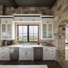 Kitchen With Stone Walls, White Cabinetry & Neutral Tile Backsplash