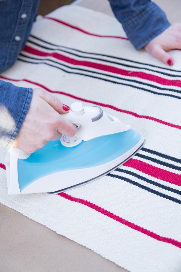 Lay the rug flat and use a hot iron to remove any folds or creases.