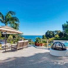 Tropical Patio With Umbrella Covered Sitting Area, Dome Fire Pit By Built In Corner Sofa and Gorgeous Ocean View 