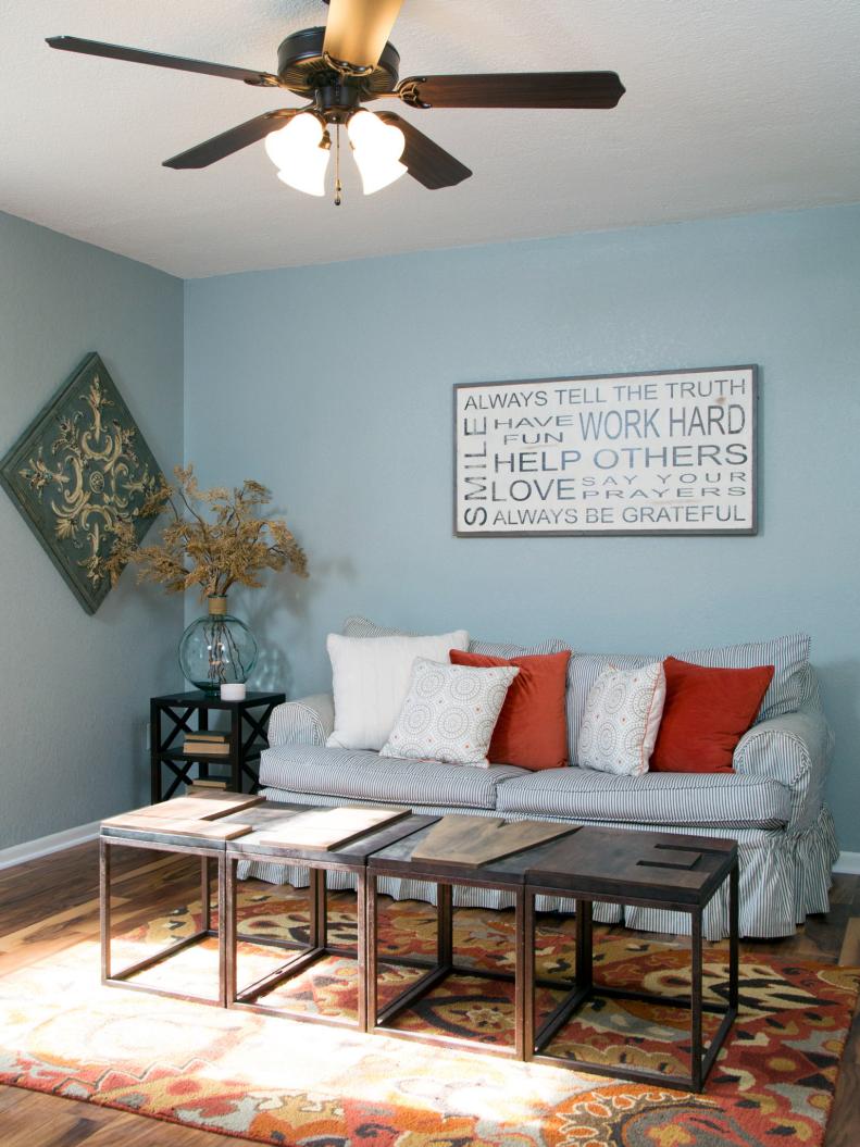 The room off the living room, which can be used as a playroom or guestroom, is staged with cozy, kid-friendly furniture and a coffee table that spells out the word â  LIVEâ  .  Faux shutters frame the windows, adding a creative look to the large wall.  New wood floors replaced the dated blue carpet, and the walls were painted a light blue, as seen on HGTVâ  s Fixer Upper.  (after)