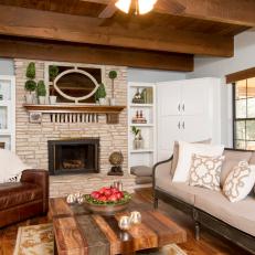 Polished Country Living Room Featuring Natural Wood Coffee Table, Leather Armchair and Textured Stone Fireplace Surround