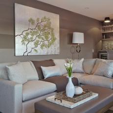 Sophisticated Transitional Sitting Room With Taupe Walls, Leather Upholstered Coffee Table and Glossy Throw Pillows 