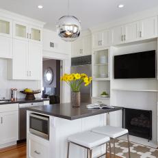 Sleek Transitional Kitchen WIth Bright, White Walls and Cabinetry, Centered Island and Built in Shelving Surrounding Black Fireplace