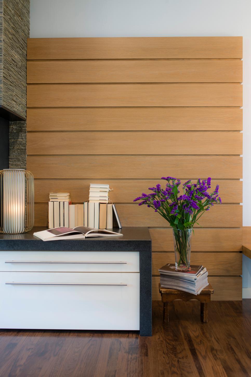 Wood Panel Wall Decor Behind Contemporary Dresser With Black Stone Top Stacked Book Display And Purple Flowers For Color Hgtv