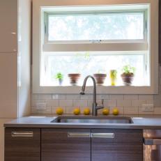 Contemporary Kitchen Sink With White Tile Backsplash, Woodgrain Cabinetry and Stainless Steel Sink