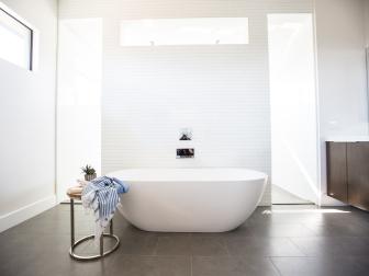 Large, minimalist bathroom with free-standing tub, in white. 