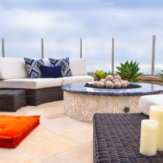 Luxurious Mediterranean Fire Pit Lounge Area With Wicker Sofas, Blue Accents and Rough Tile Fire Pit Base