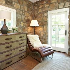 Stone Cottage Bedroom Nook with Modern Leather Lounge Chair, Stone Walls and Antique Dresser