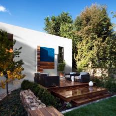 Backyard Area featuring Tiered Wood Deck, Benches, Grass Lawn and Modern Art