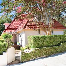 White Home With Red Tile Roof Surrounded by Boxwood Shrubs