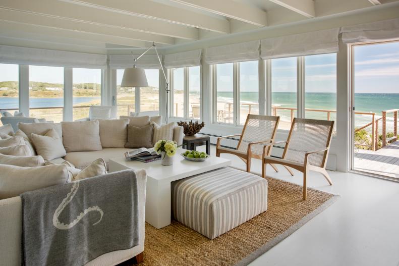 White, Coastal Living Room With Wall of Windows, Neutral Furniture