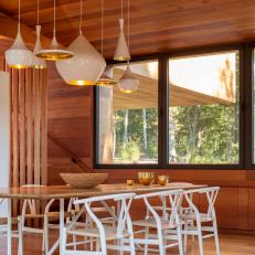 Modern Wood-Paneled Dining Room With White Pendants