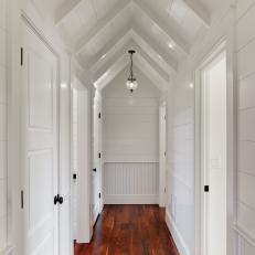 Crisp White Hall With Rich Wood Floors & Angled Ceiling