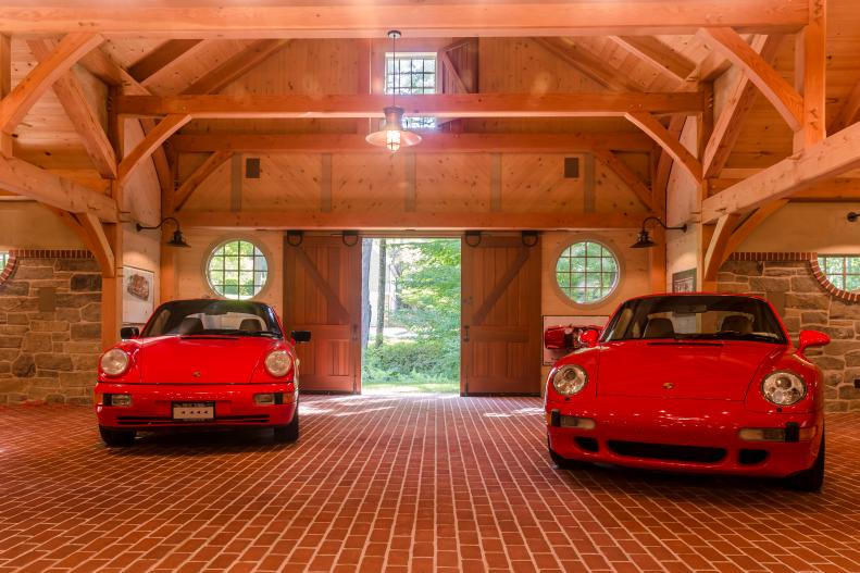 Two Red Cars in Timber-Frame Building With Brick Floors