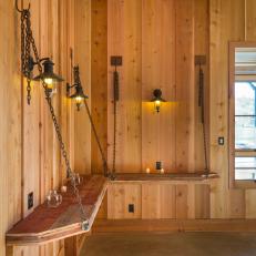 Chain-Hung Shelves With Lanterns on Untreated Wood Walls