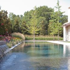 Modern Home's Swimming Pool with Concrete Fountain and Nearby Wildflowers