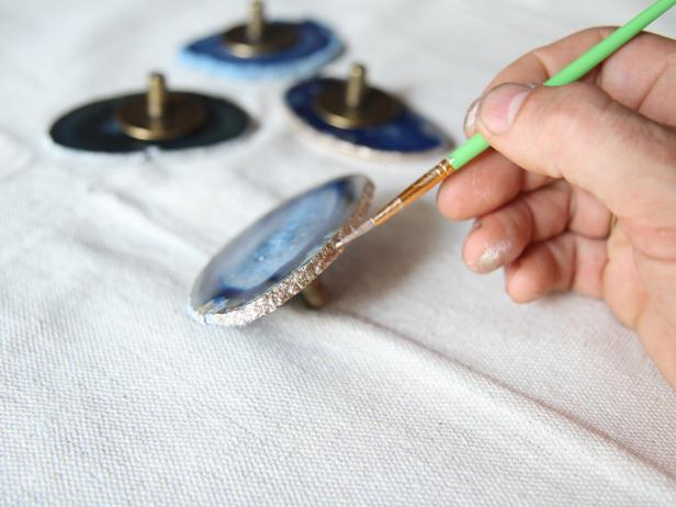 Using a fine tipped paintbrush, paint the edges of each stone with metallic gold paint.