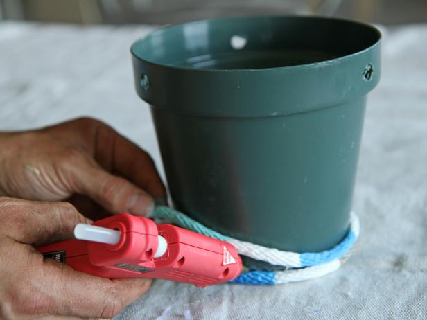 Apply glue and wrap the rope around the plastic pot, working one section at a time.
