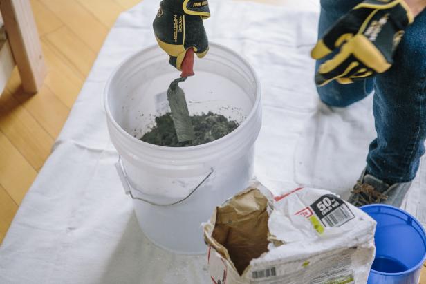 Mix concrete in a plastic bucket with a trowel until you get a cake batter-like consistency.
