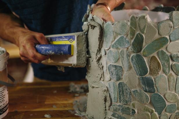 Apply grout to tile sheets using a grout float.