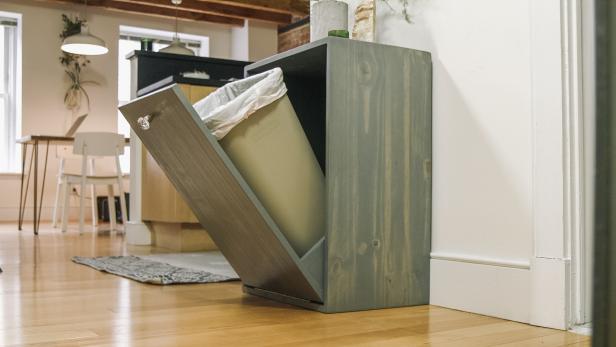 a cabinet with a door that opens to a hidden trash can