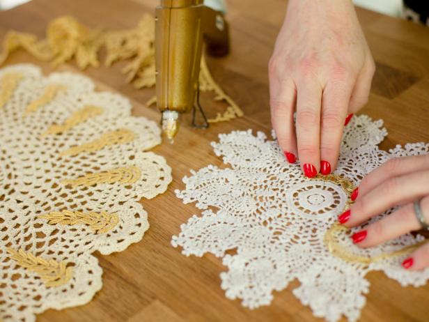 For some doilies, simply hot glue gold trim in a circular pattern or along the edges. For others, use a glue gun to attach trim in fun and interesting ways.. Get creative and play up the intricate design of each doily.
