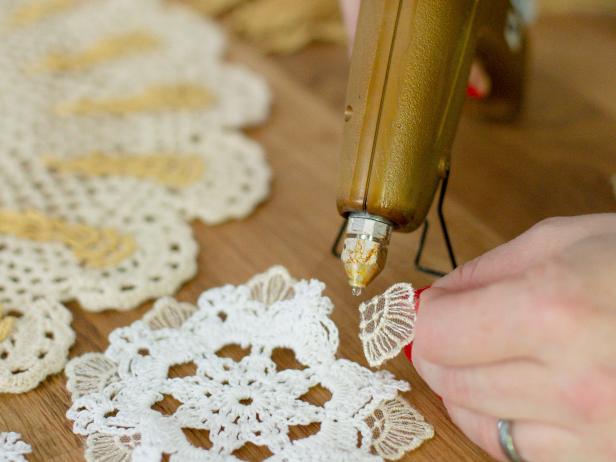 For some doilies, simply hot glue gold trim in a circular pattern or along the edges. For others, use a glue gun to attach trim in fun and interesting ways.. Get creative and play up the intricate design of each doily.