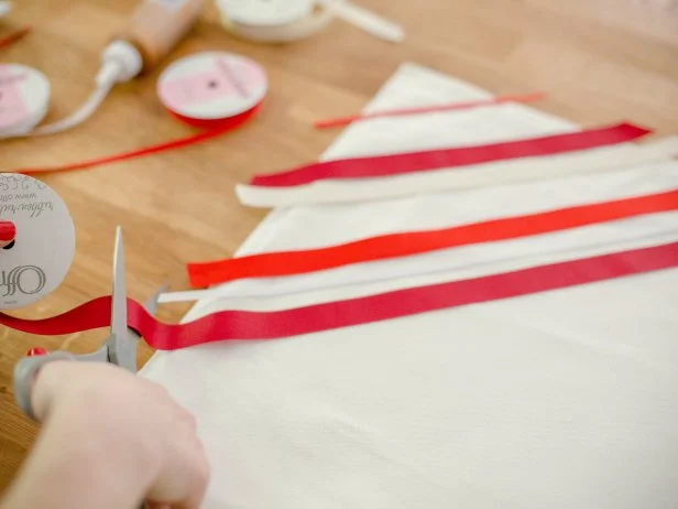 Roll out the ribbons in a diagonal across the pillow cover, alternating ribbon color and type, cut so that there is a 1 inch overhang on either side. Leave the spacing between ribbons slightly random and pin into place, as you work your way down.