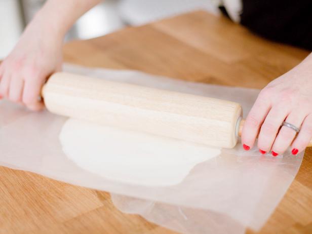 Roll the clay into a nice tight ball and place on wax paper. Place another piece of wax paper on top of the ball and press down until flattened. Next, use a rolling pin to further flatten the clay to about .25 inch thickness, then remove the top layer of wax paper.