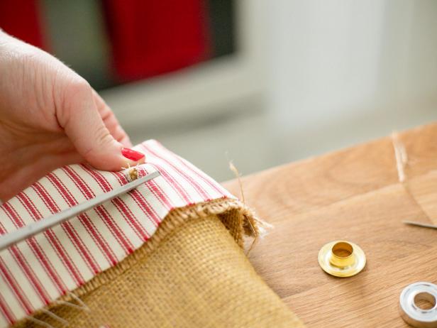 Once you determine the grommet's placement in the upper corner of the sack, make a mark using a pen or pencil. Then, using scissors, snip a hole through the fabrics- this is where you'll slip one side of the grommet through from underneath. Next, using a hammer and grommet setter, attach the top side of the grommet and set into place.