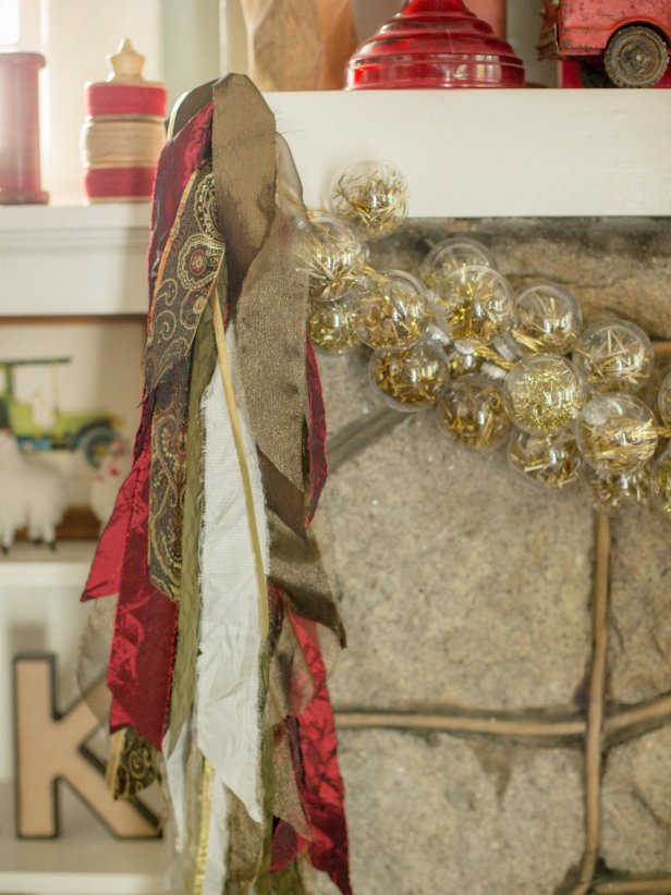 Knot the ends of the gold cord, then, using adhesive hooks and gold ribbon, hang the garland across the mantle horizontally. Next, hang the fabric swags on either side, vertically