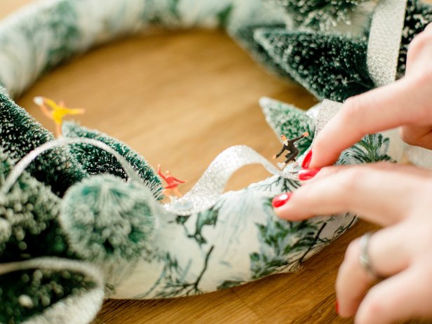 Using a dab of hot glue, secure each of the miniature figurines onto the ribbon. Once glue has cooled, hang wreath and enjoy!