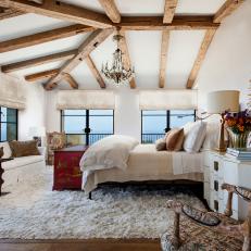 White Master Bedroom with Large Windows, Exposed Ceiling Beams and Flokati Rug