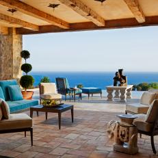 Large Outdoor Porch with Stone Floors, Turquoise Upholstered Sofa and Ocean View