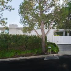 White Midcentury Modern Ranch Home with Privacy Hedges and Gate