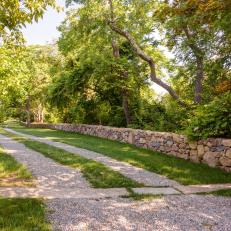 A Gravel Ribbon Driveway Framed by a Stone Wall